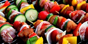 Vegetable and meat kebabs skewered with colourful bell peppers, chicken, red onion, cherry tomatoes and zucchini on a grill