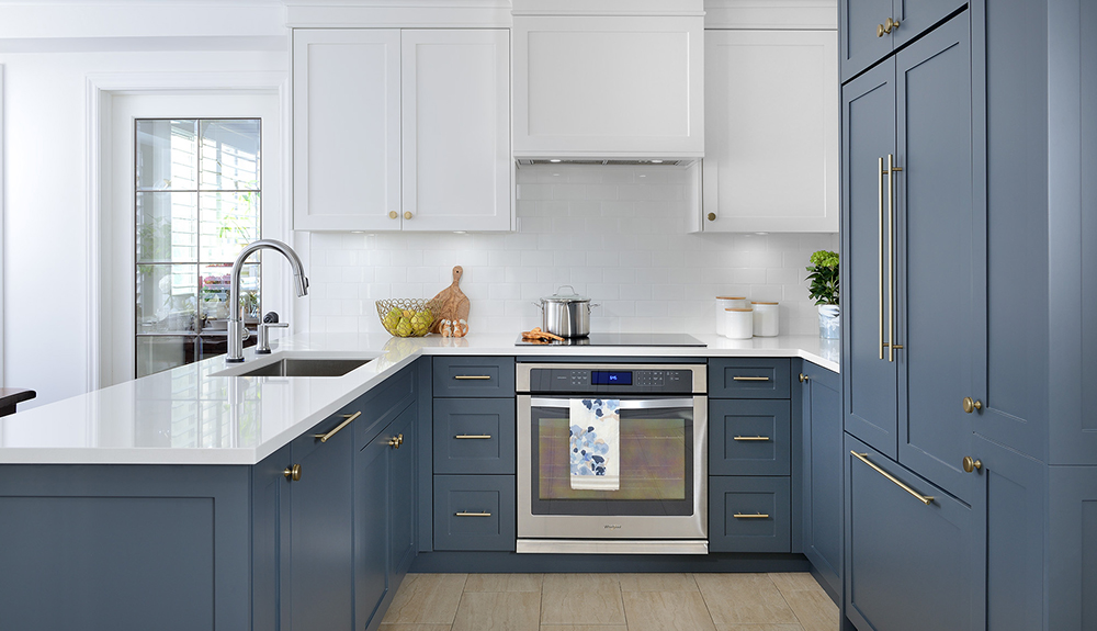 A clean and contemporary kitchen with white countertop, silver oven and blue-grey painted wooden cabinets and simple silver fixtures