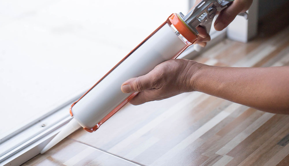 Caulking the bottom of a sliding door.