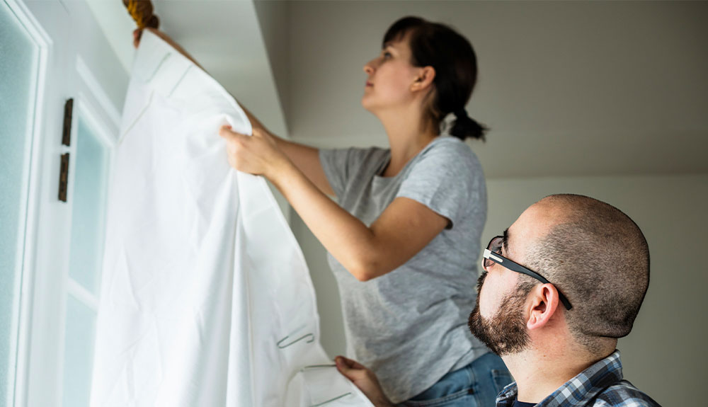 A couple hang curtains.