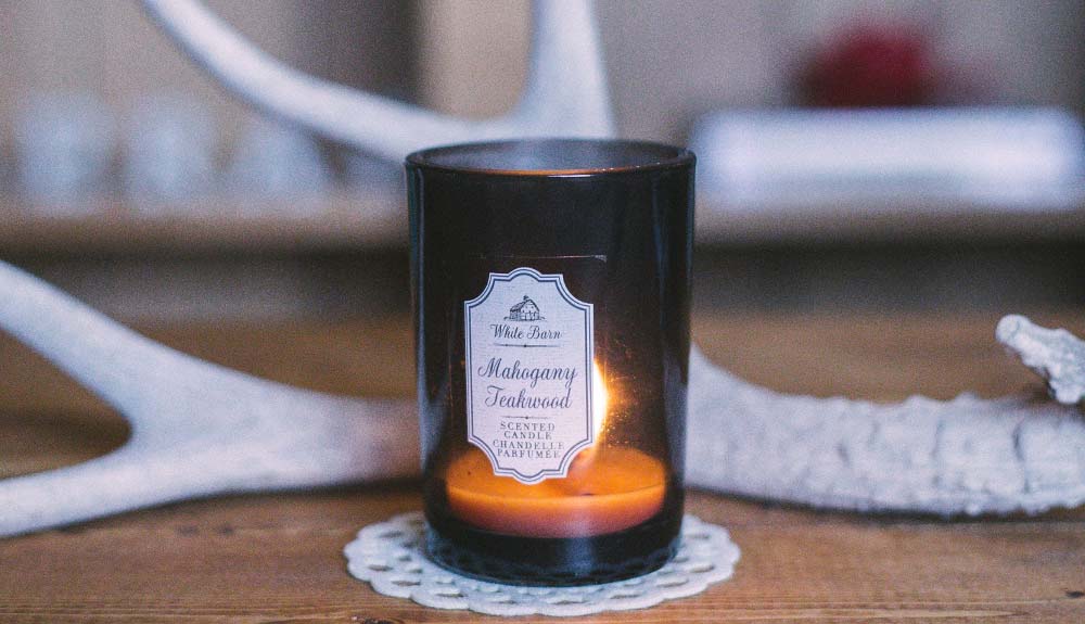 Candle on a wooden table with an antler behind it