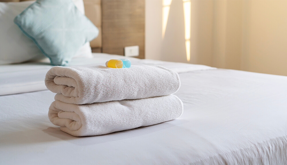 White towels stacked neatly on top of bedspread