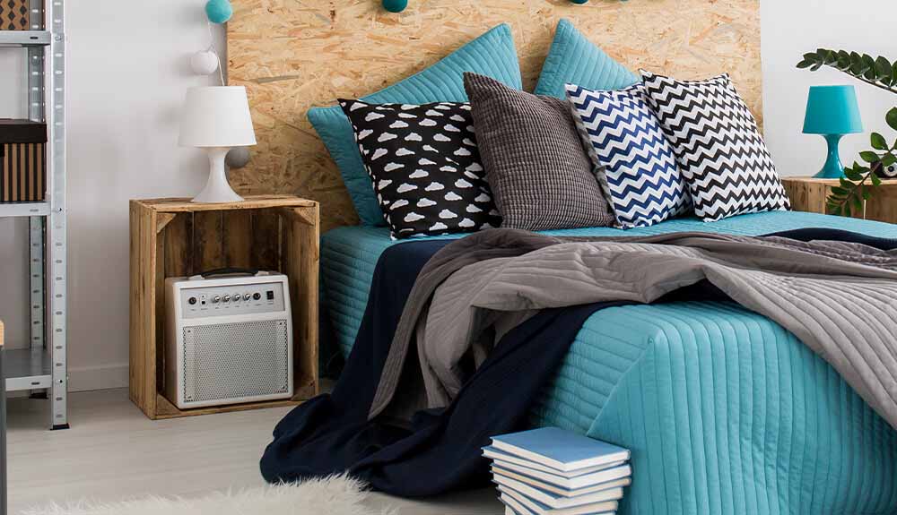 Bed made with bright turquoise blanket and black and white pillows