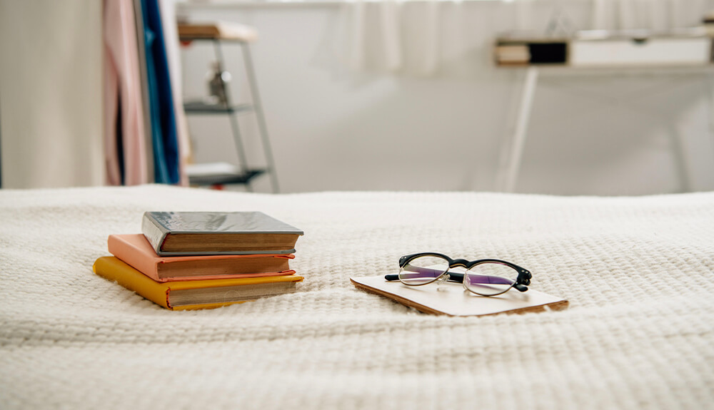 Books and reading glasses laid out on bedspread