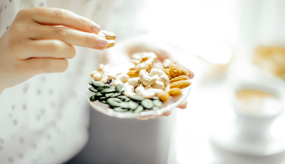 Person holding a small dish of nuts and pumpkin seeds