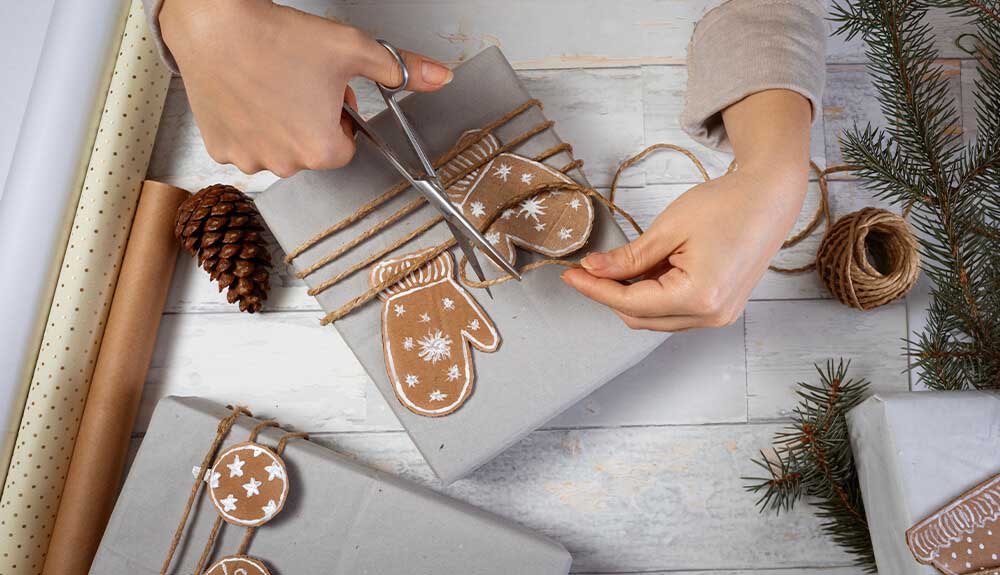 Person using scissors to cut twine after winding it around a gift-wrapped box