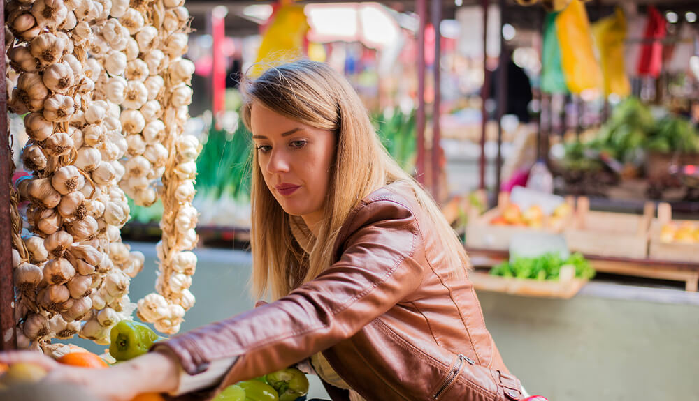 Woman reaching for fresh produce at farmers' market