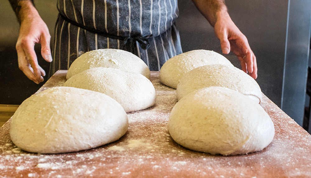 Six loaves of raw sourdough dough ready for the oven