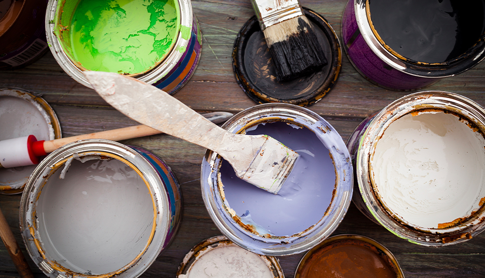 Several cans of paint with paint brushes