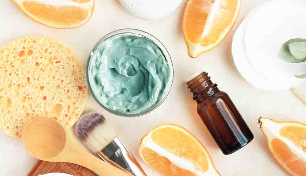 A collection of personal care products, including oranges,  oils, and a scrub brush.