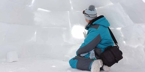 A young person builds an igloo out of snow