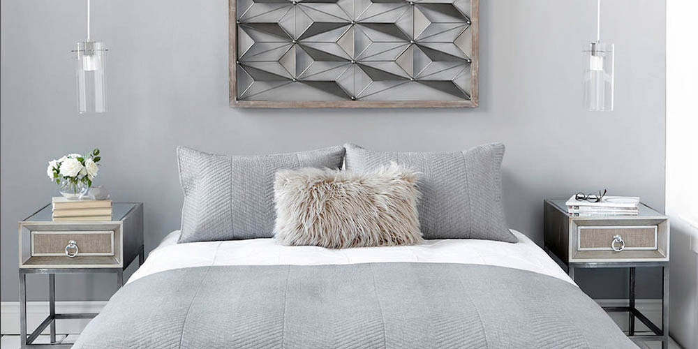 A grey bedroom stylishly decorated with pendant lights, a painting and grey side tables.