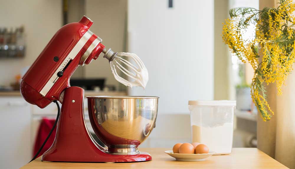 A red stand mixer is shown on a kitchen counter