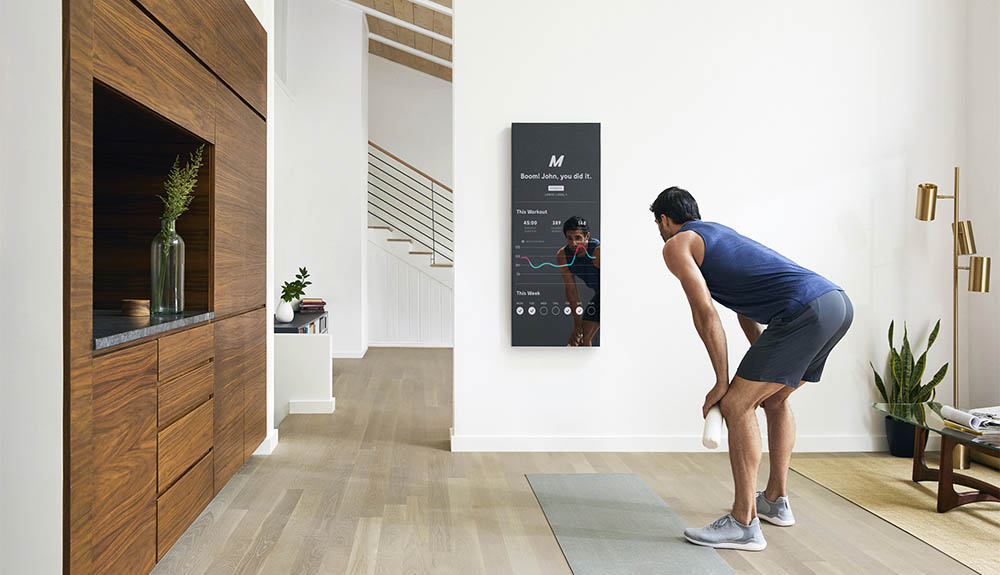 A man stands in front of the Mirror, which displays stats about his workout