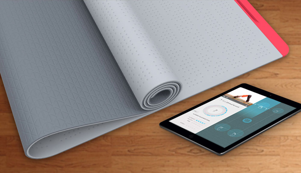 A SmartMat yoga mat is rolled up on the floor next to an iPad