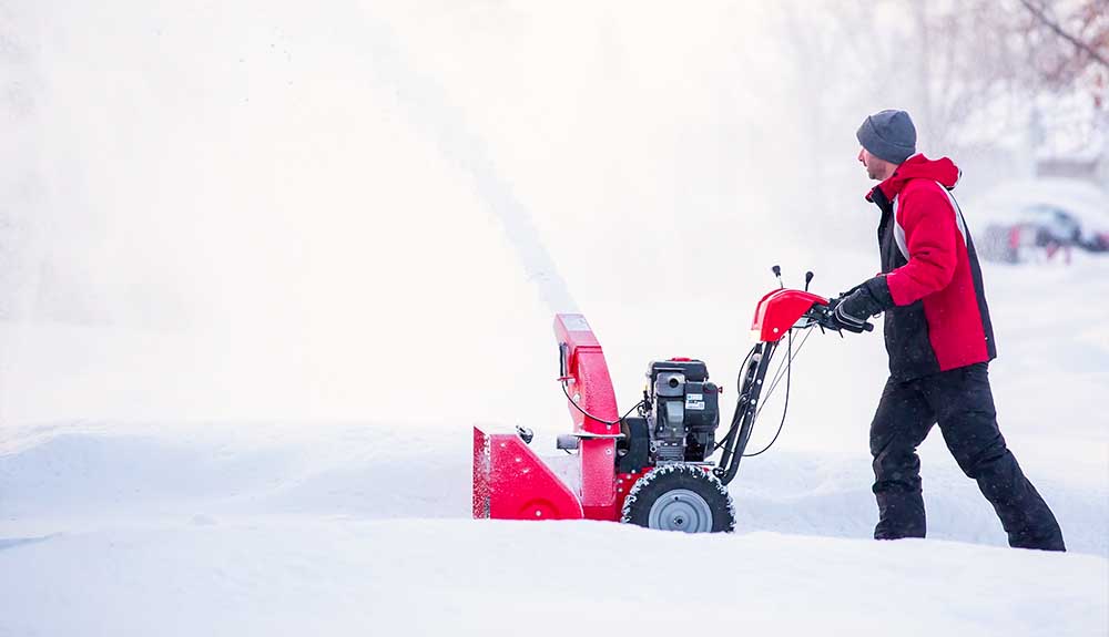 A person is shown using a snowblower in deep snow