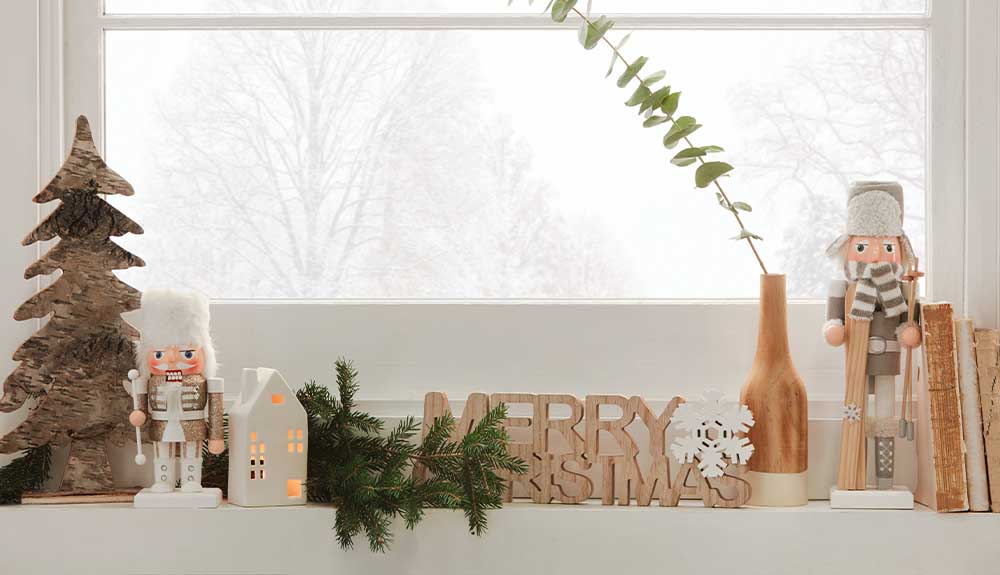 A ledge with Christmas decorations is shown below a window