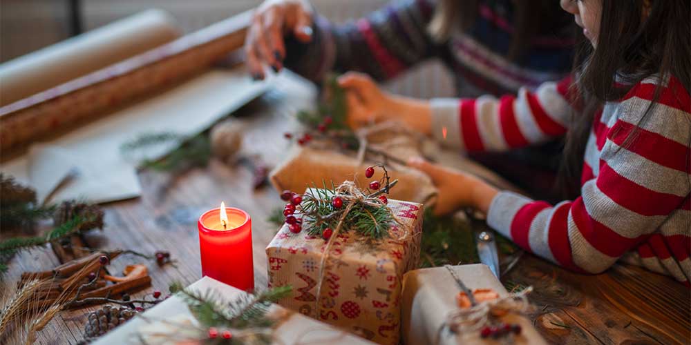 Kids are shown unwrapping presents with a candle in the foreground