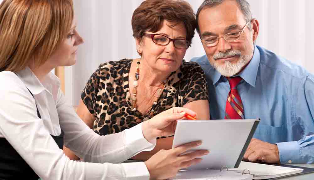 An older couple sit with a young woman to look at paperwork