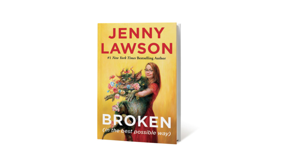 The cover of Broken is shown with a yellow background and an illustration of a woman holding a furry creature