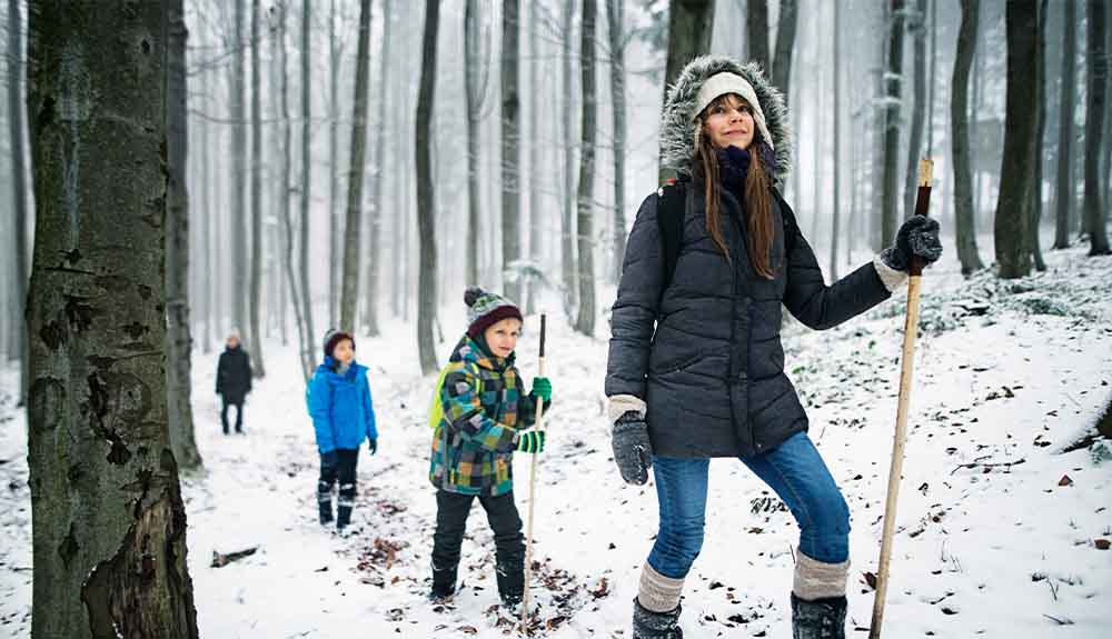 A family hikes along a path in the winter