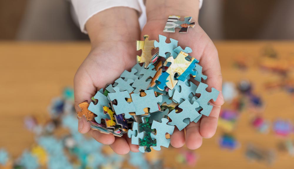 A child holds a large handful of puzzle pieces