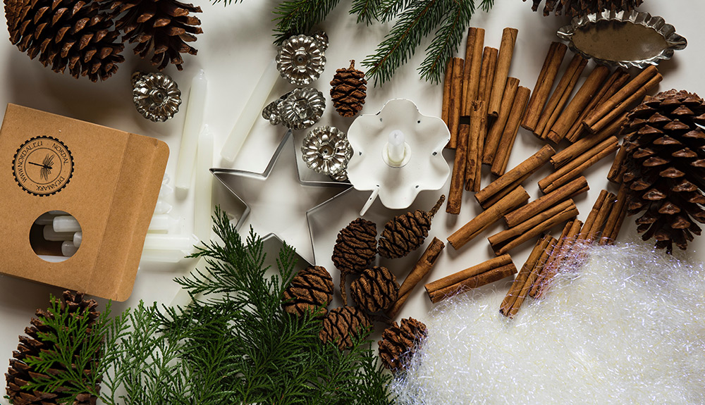 An overhead view of fake snow, tinsel, cinnamon sticks, pinecones and cookie cutters