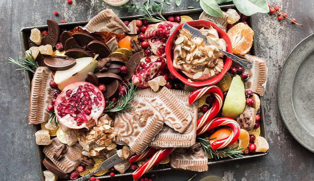 Holiday tray with gingerbread cookies, candy canes, a sweet spread and fresh fruit