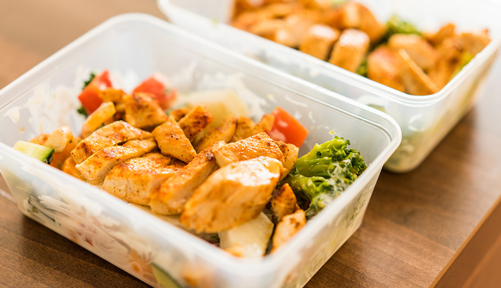 Plastic containers with leftover vegetables and chicken packed neatly inside