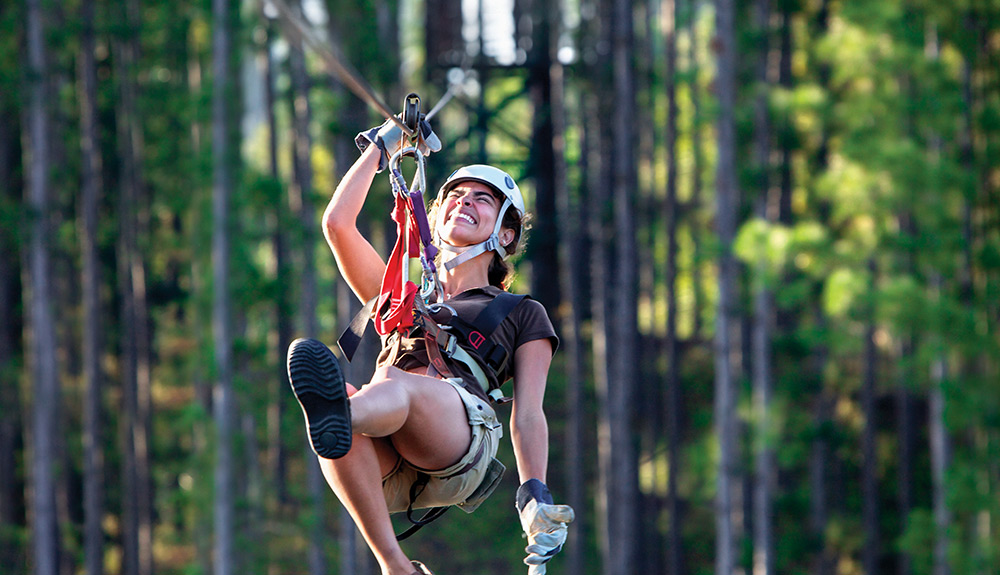 A woman laughs with delight while ziplining in Las Terrazas