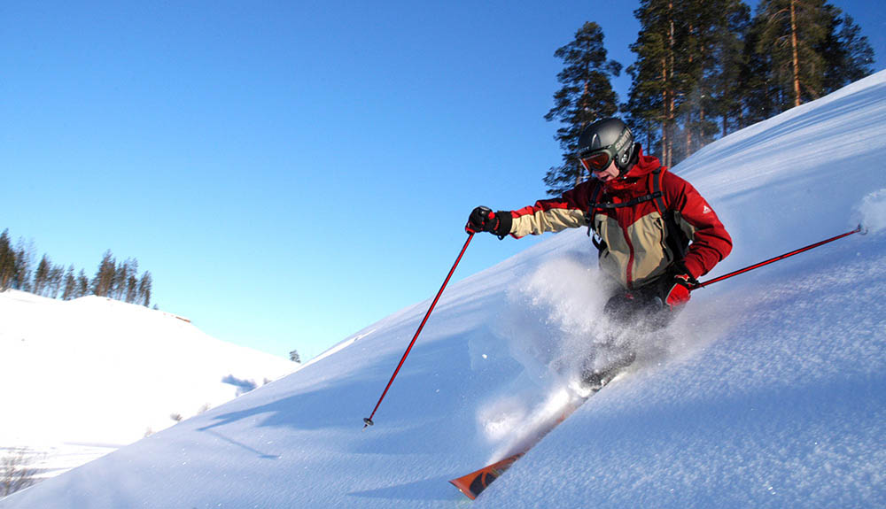 A skier sprays snow as they glide down a hill with fresh snow