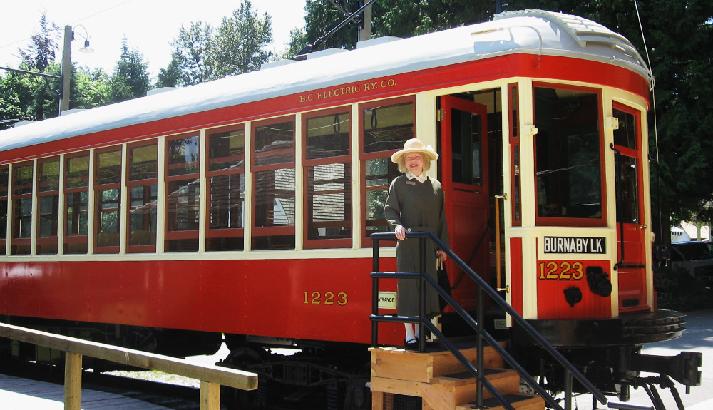 A woman stands on the steps to board the red vintage tram at the Burnaby Village Museum in Burnaby, Canada