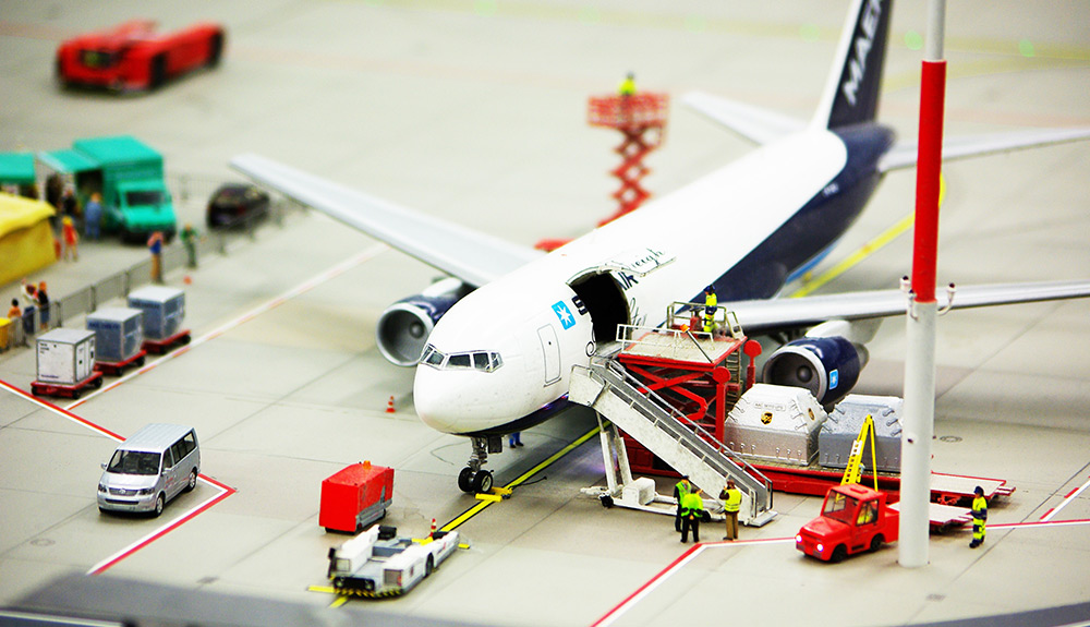 Model airplane on play runway, toy workers loading the cargo bay