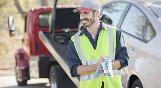 Tow truck driver with tow truck in background