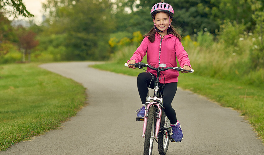 Yonge girl riding a bike in a park.