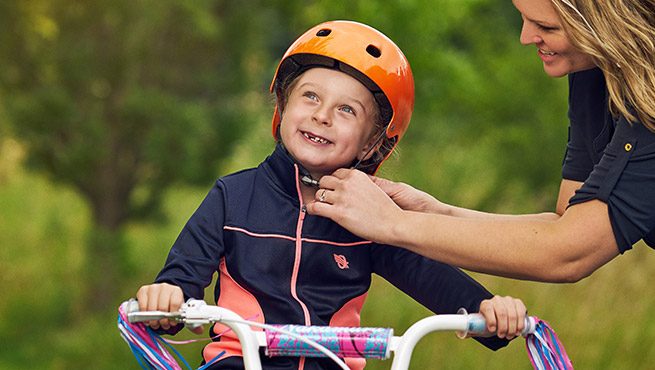 Mother helping her kid with the helmet 