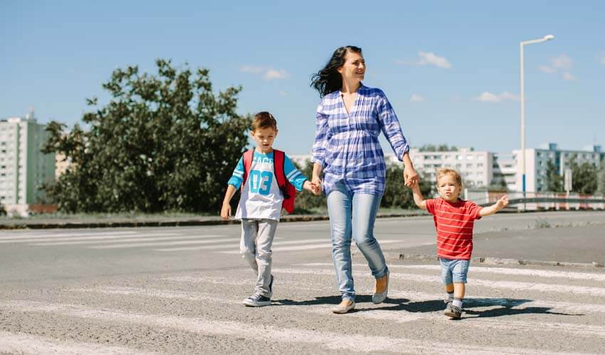 Mother and her children crossing a road on way to school in the morning