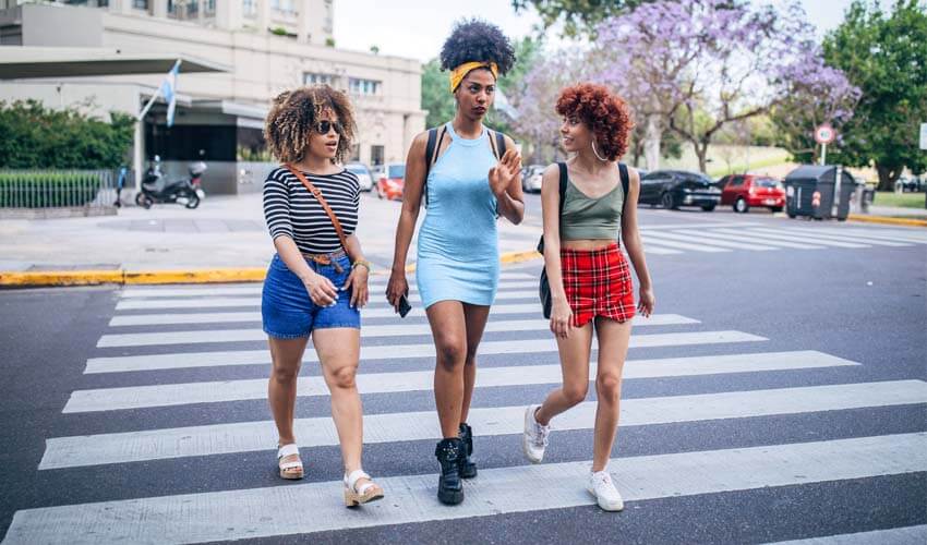 Three of women walking on the city street together.