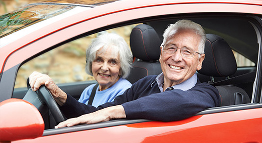 Senior couple driving red car