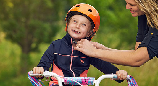 Mother putting bicycle helmet on child.