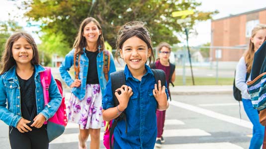 Group of smiling school children crossing the street