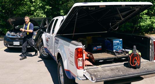 CAA driver carrying car battery to truck