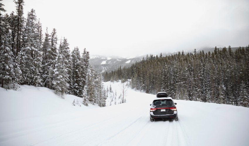 Car driving on snow covered remote road.