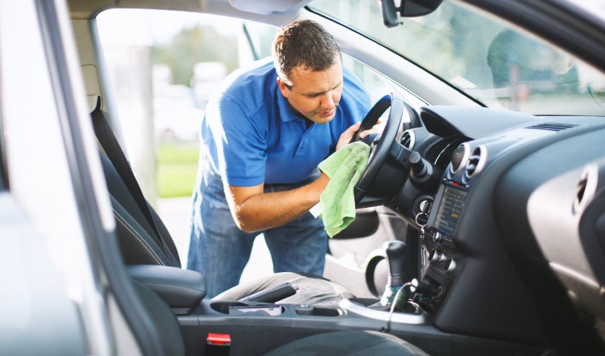 Man wiping down his car steering wheel.
