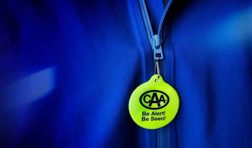 Fluorescent CAA reflector tag attached to zipper on blue jacket