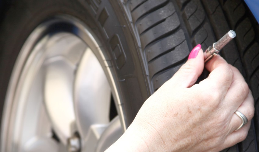 Woman check tire tread on vehicle