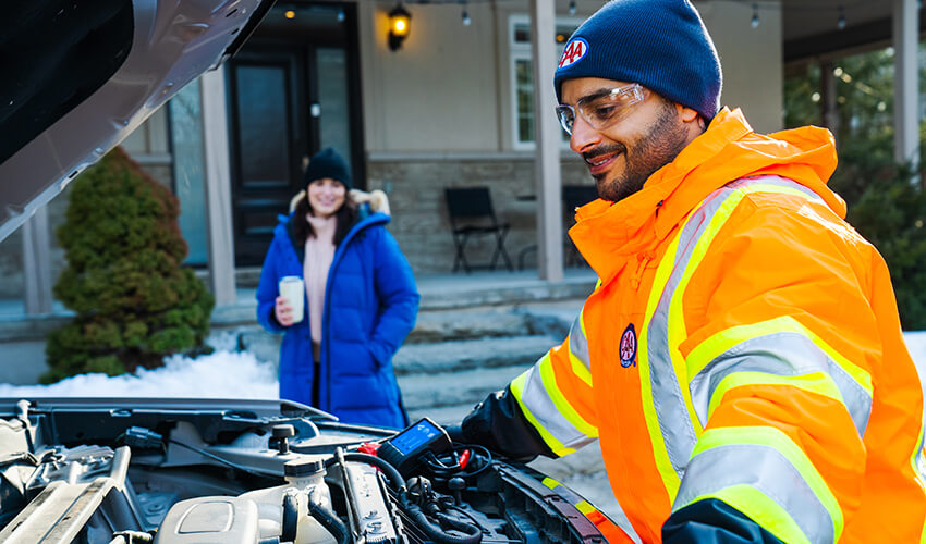 CAA trained technician testing a car battery by a customers home.