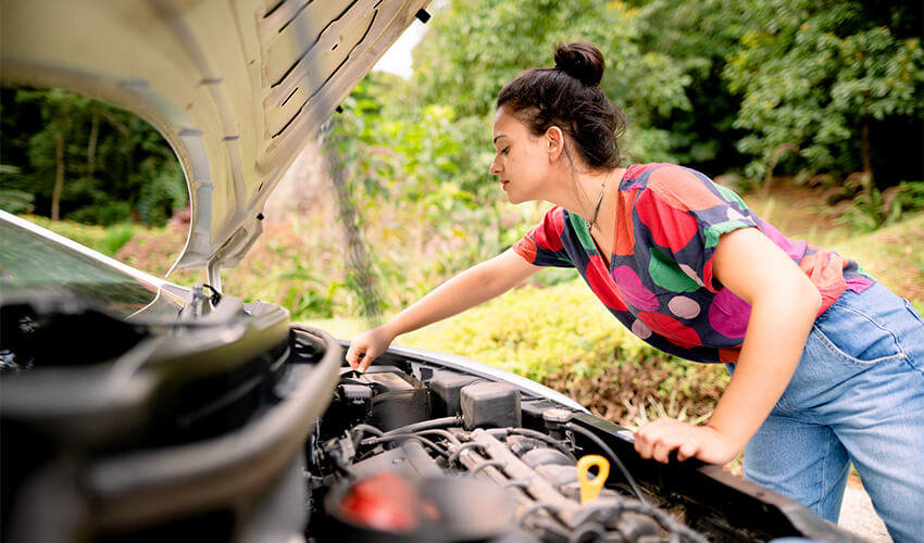Woman checking car battery in the summer.