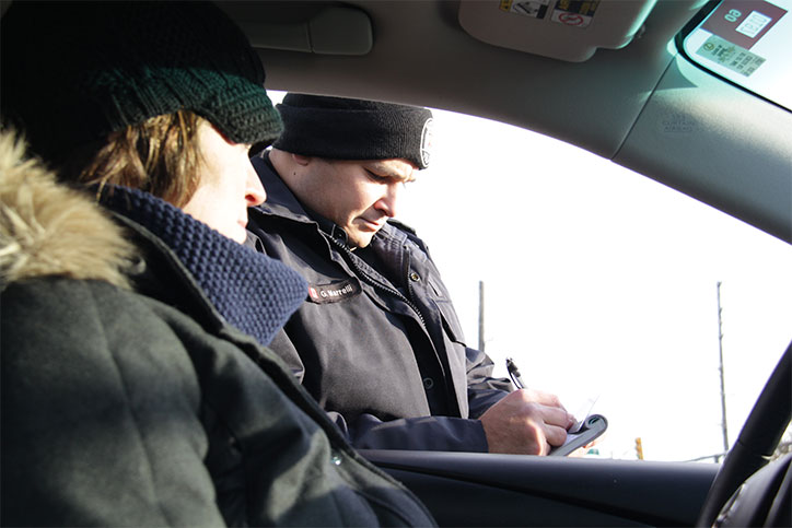 Police officer at the driver's window writing a ticket