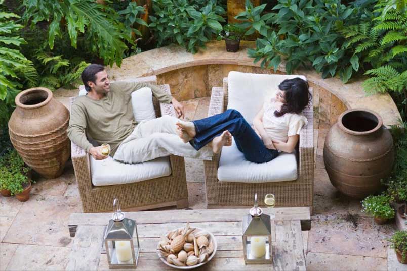 Couple seated on wicker chairs on designer inspired patio.